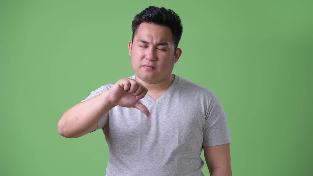 초록색 배경에 젊은 잘생긴 과체중 아시아인