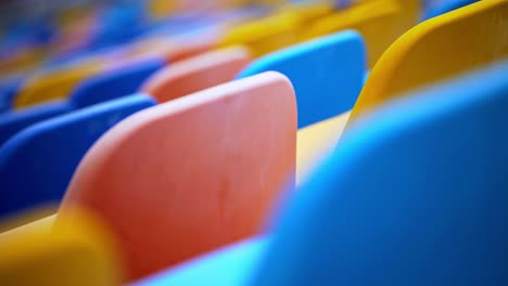 sillas de varios colores en el estadio. filas de asientos de plástico vacíos en la arena