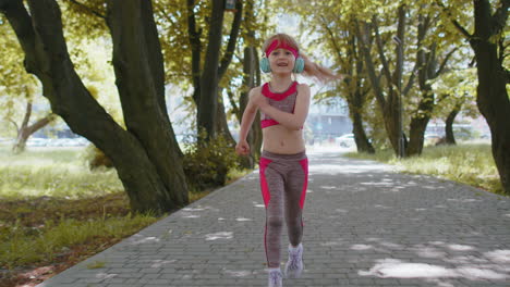 Athletic-fitness-sport-runner-girl-kid-training-marathon-run,-listening-music-in-headphones-in-park