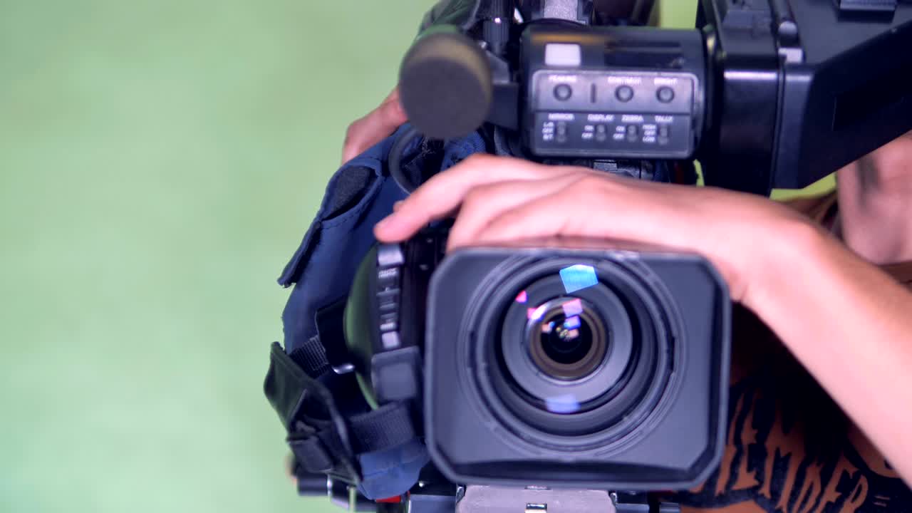카메라맨이 캠코더를 재방향하고 외부 렌즈를 회전시키고 있습니다.