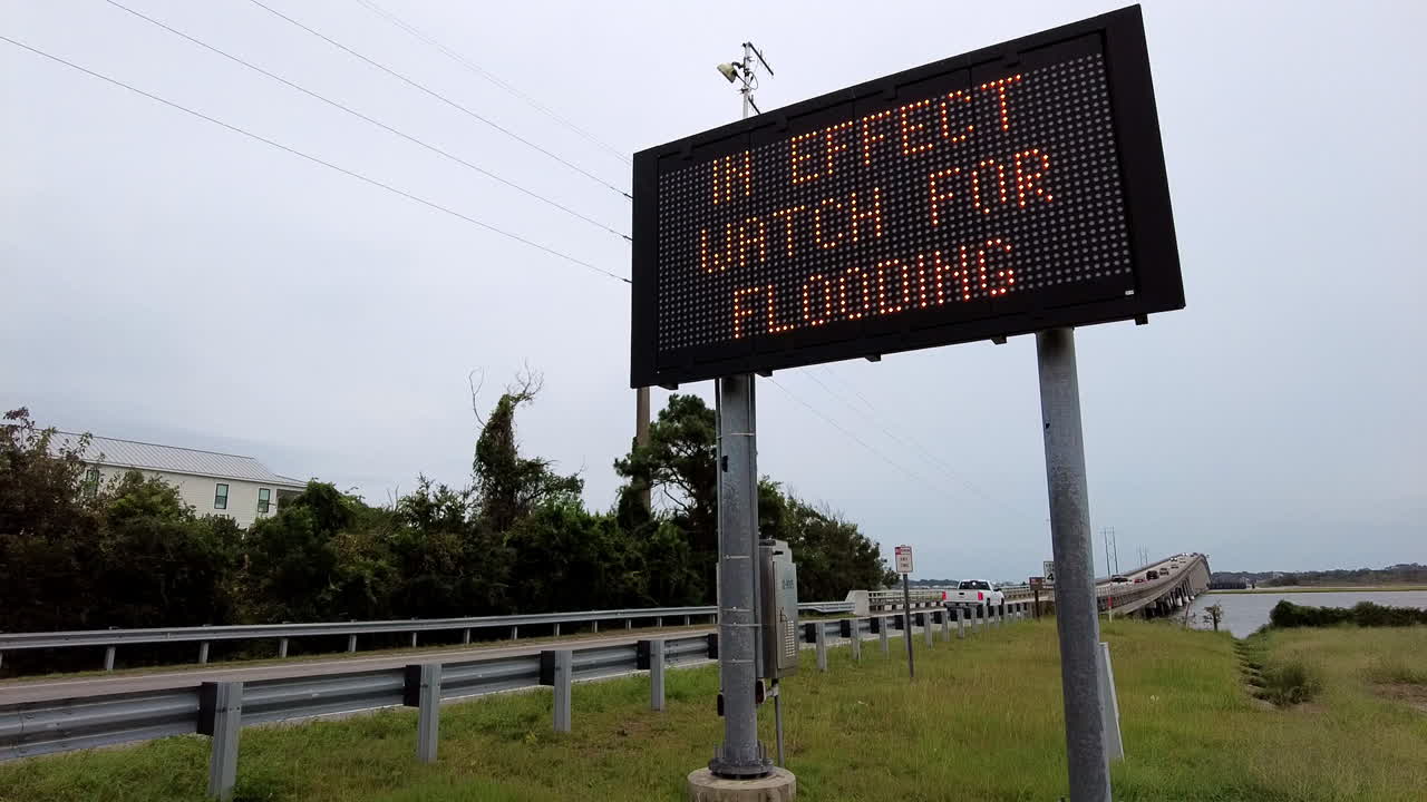 열대 폭풍 경고 표지판이 해안 다리에서 표지판에 박이고 있습니다.