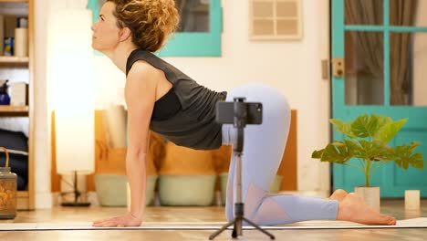 mujer haciendo asana marjaryasana mientras practica yoga en una clase en línea