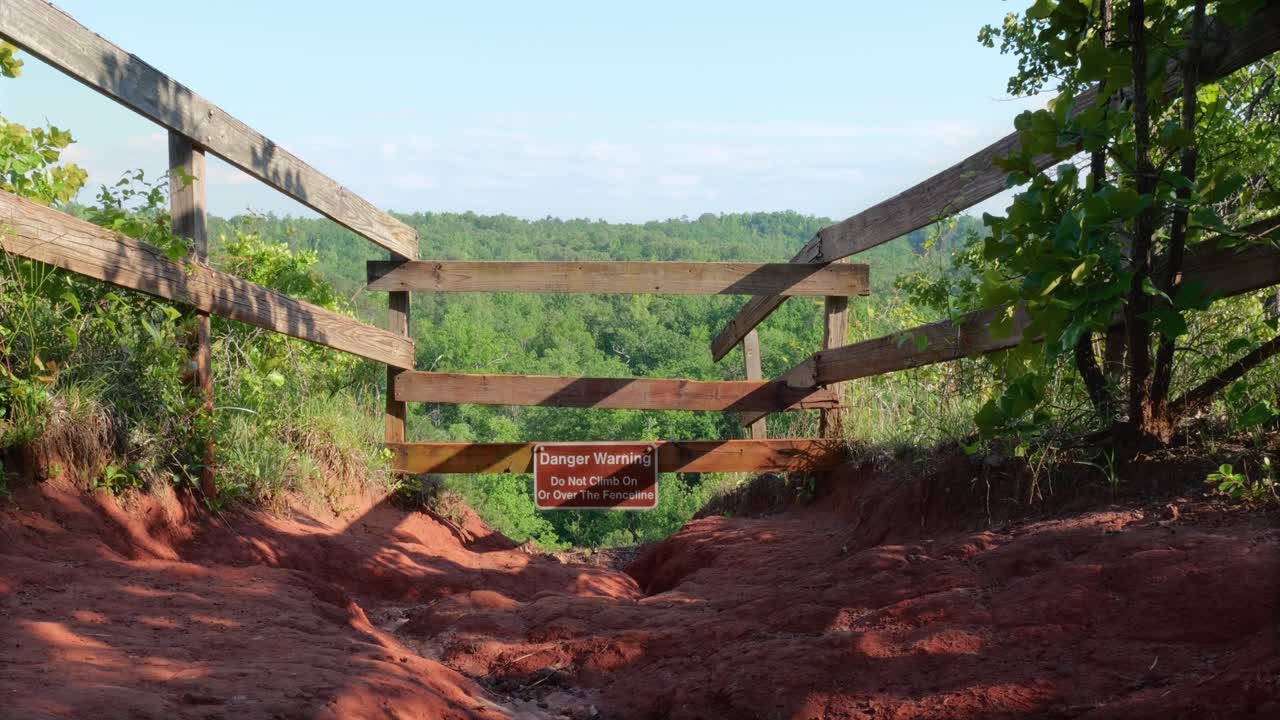 ruta de senderismo de arcilla que conduce a un letrero de peligro con vistas al cañón en el parque estatal providence canyon en lumpkin, georgia, visto en un soleado día de primavera