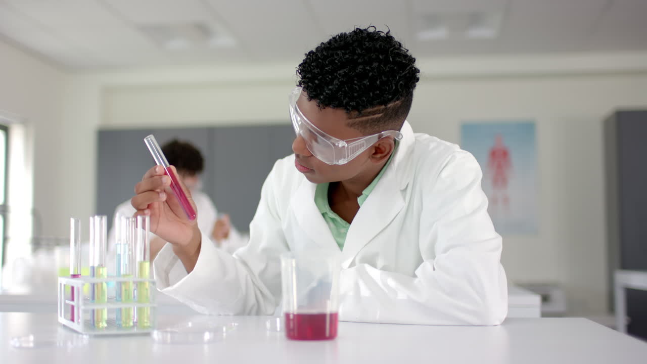 A teenage biracial boy examines a test tube in a lab