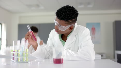 a teenage biracial boy examines a test tube in a lab