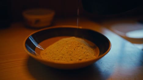 a person pours hot water over a bowl of traditional norwegian grain porridge in a warm, rustic cabin setting in reinsjøen, åfjord, trøndelag, norway - close up