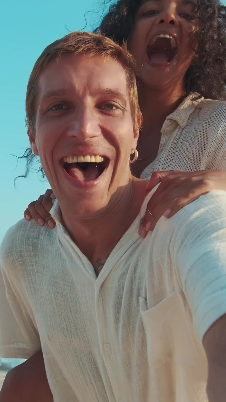 Una coppia si gode la spiaggia scattandosi un selfie al tramonto.