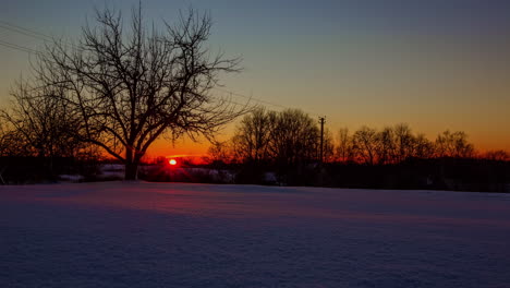 Puesta-De-Sol-Naranja-Brillante-En-Un-Día-De-Invierno-Sobre-El-Campo-Nevado-Europeo---Lapso-De-Tiempo