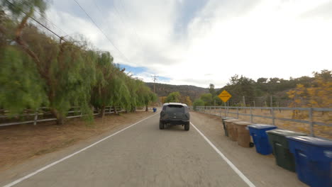 fpv follow shot of a rezvani driving and braking on a town road in california