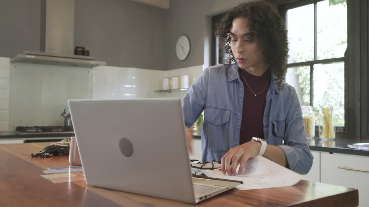 Holding paper non-binary person reading in kitchen then typing wiping island with towel, copy space