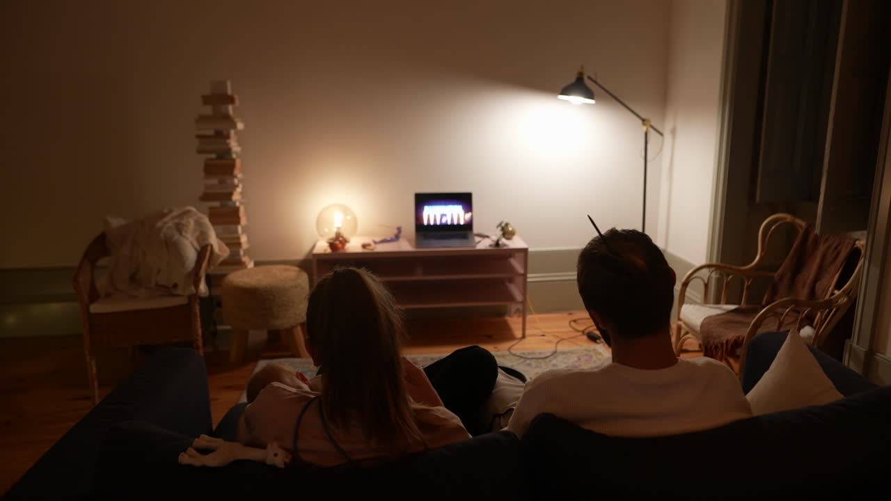 커플과 아기가 밤에 tv를 보고 있습니다.