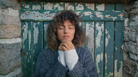 frustrated model covering face posing door outside closeup. curly girl praying