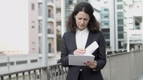 mujer de negocios seria leyendo periódicos