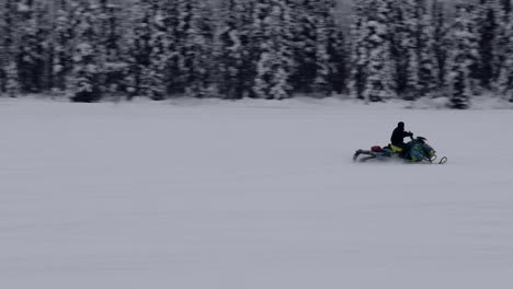 snowmobile traveling across winter landscape, tracking shot