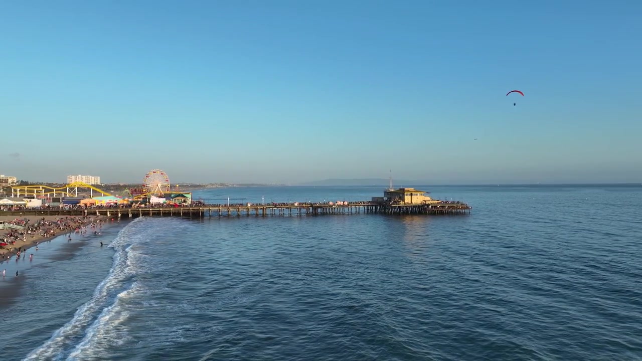 Los Angeles'ta gün batımında Santa Monica İskelesi'nin etrafında dönen bir uçurtmanın havadan görünümü.