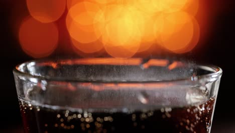 Cola-Mit-Spritzenden-Blasen-In-Zeitlupe-Auf-Verschwommenem-Licht,-Verschwommenem-Hintergrund.