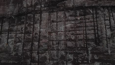 close-up of a weathered concrete wall with visible rebar grid patterns, exhibiting signs of decay and corrosion