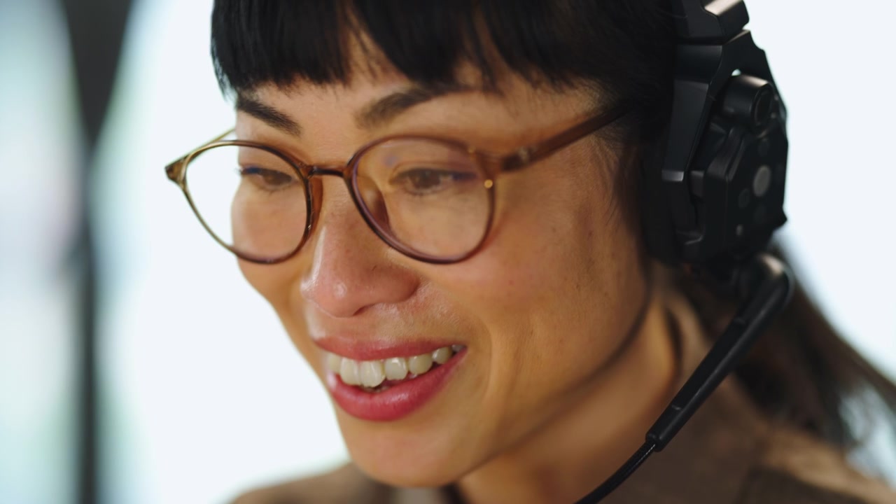 Donna Asiatica con Cuffie che Lavora nell'Ufficio Assistenza Clienti