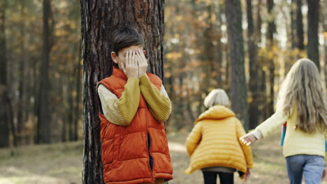 lindos niños caucásicos jugando al escondite en medio del bosque en un día soleado