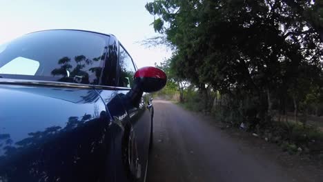 hatchback car running at high speed among tropical forest, dusty road