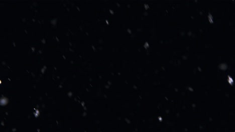 rapidly falling snowflakes flurrying around in a black winter night