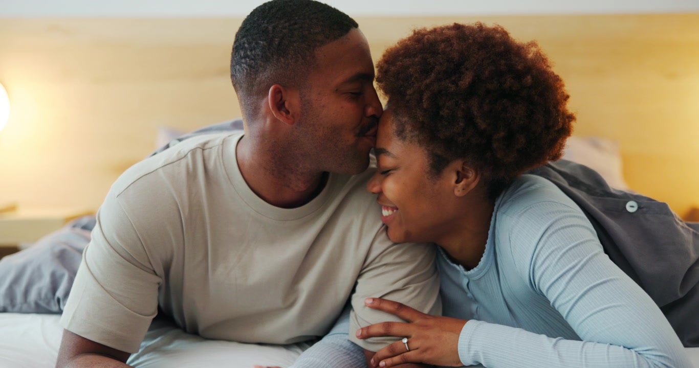Loving Young Couple Cuddling and Kissing in Bed