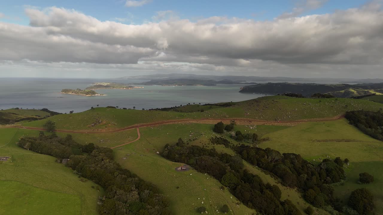 Stony Batter Historic reserve on waiheke island, New Zealand. Green idyllic hills landscape at cloudy evening. Seascape in distance. Peaceful memorial landmark. Aerial wide shot