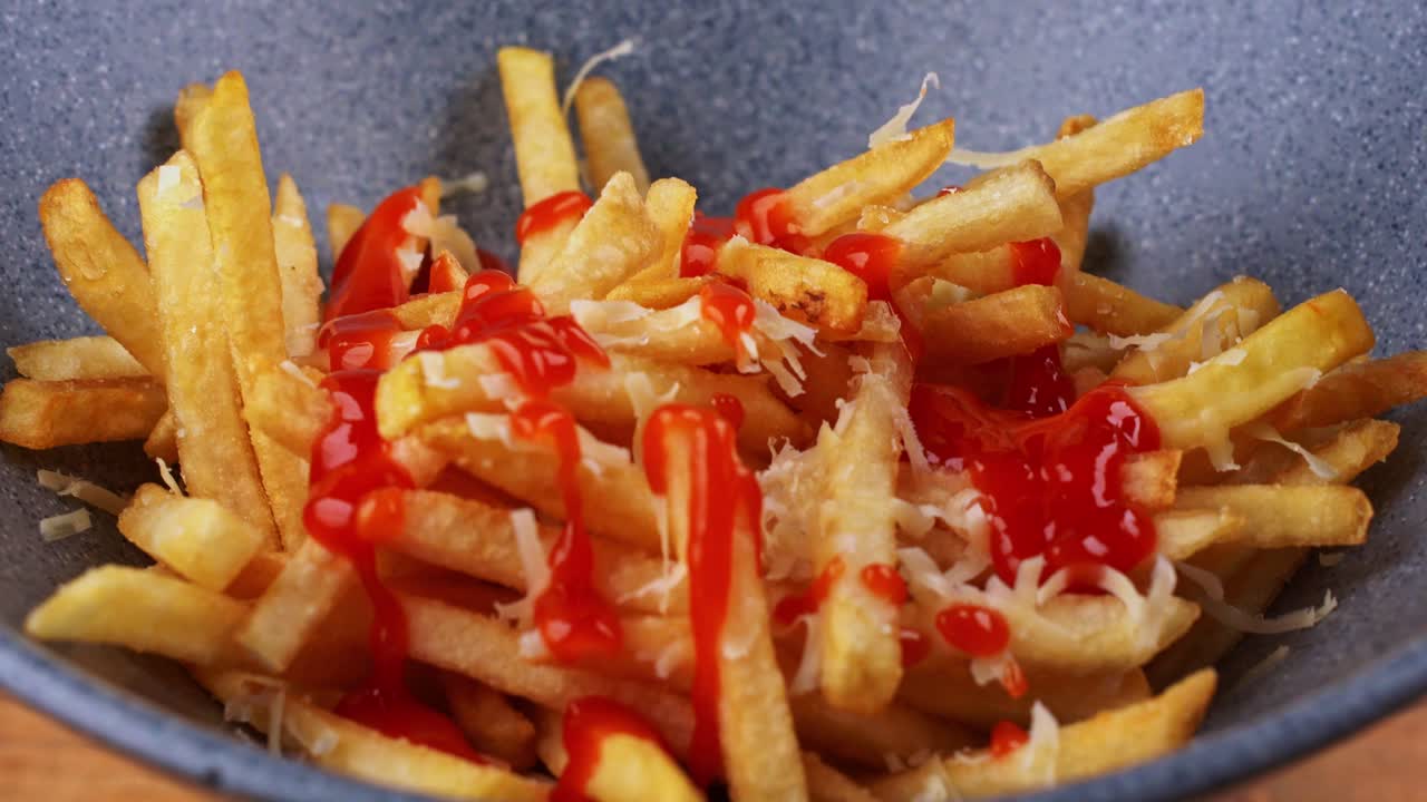 Detailed close up of grated cheese French fries smothered in ketchup