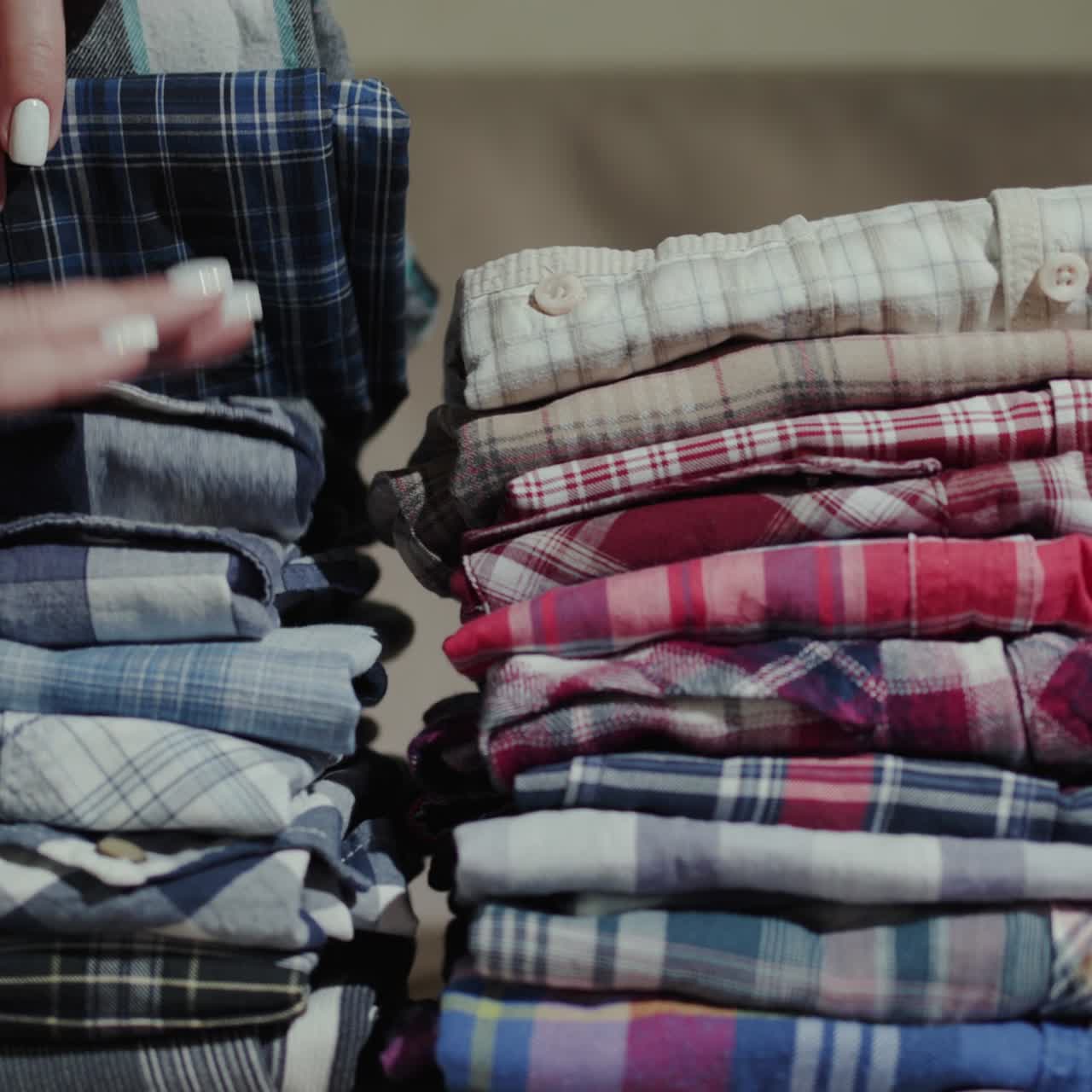 Women's hands sort through a stack of men's shirts 2