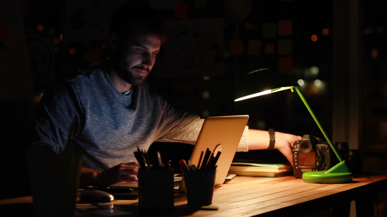 Uomo d'affari informale che usa un laptop e una fotocamera di notte