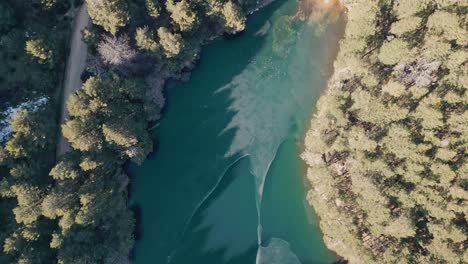 aerial view of a partially frozen lake in the middle of the forest