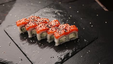 rolos de sushi de salmón en un plato de pizarra