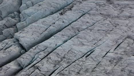 drone shot looking straight down and moving to the right, revealing more of the interesting and beautiful patterns, lines and cracks of the ice glacier