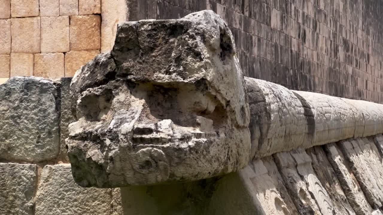 Handheld close-up panning shot of a stone serpent carving at the Great Ball Court in Chichen Itza, Mexico. 4K