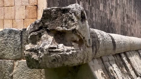 handheld close-up panning shot of a stone serpent carving at the great ball court in chichen itza, mexico. 4k