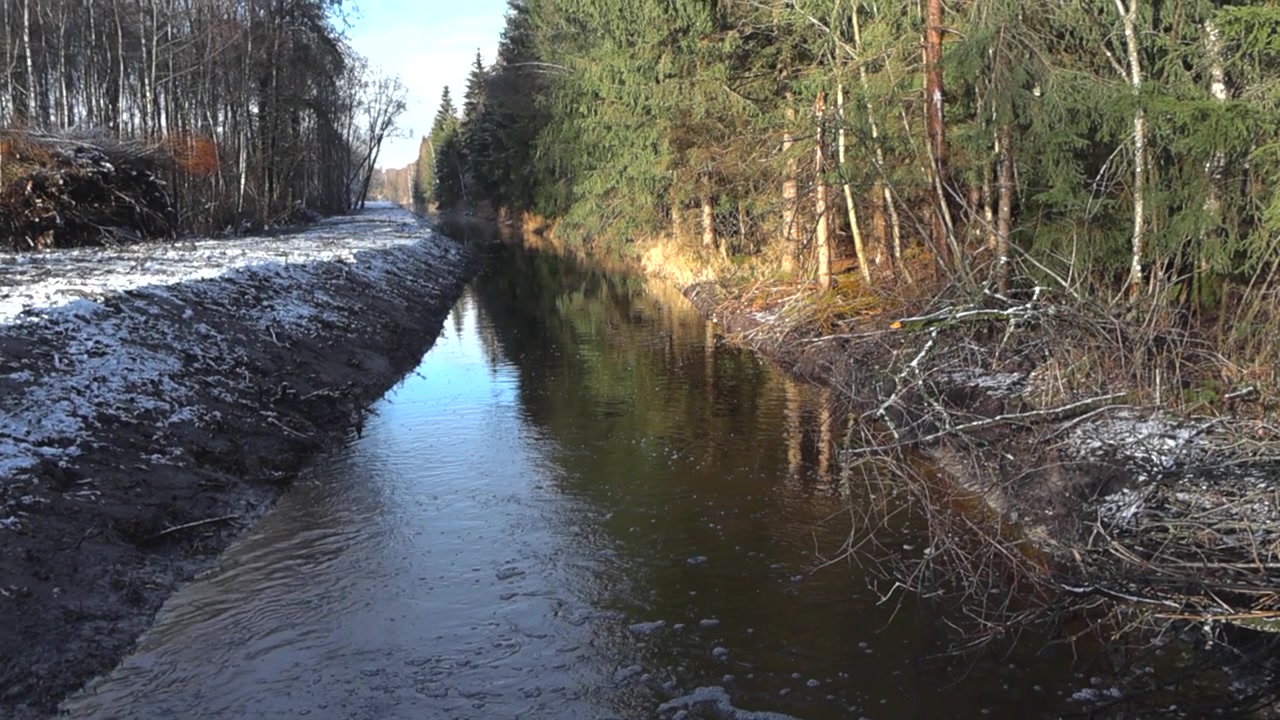 Draufsicht auf dunkelbraunes Flusswasser, das an einem sonnigen Wintertag mit hoher Geschwindigkeit fließt und dabei Weißwasser, Wellen und Wasserspritzer erzeugt. Rauschende und schnelle Bewegung, während braune Erde oder Schmutz am Ufer sichtbar ist.