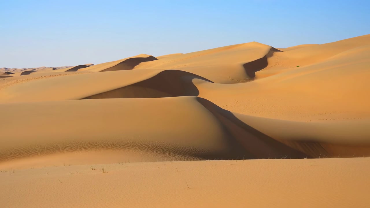 Dune di sabbia del deserto, scena statica, senza azione, in un paesaggio desertico con cielo sereno, con dune di sabbia, cielo azzurro limpido, da una prospettiva aerea o dall'alto, con accenti marroni e blu