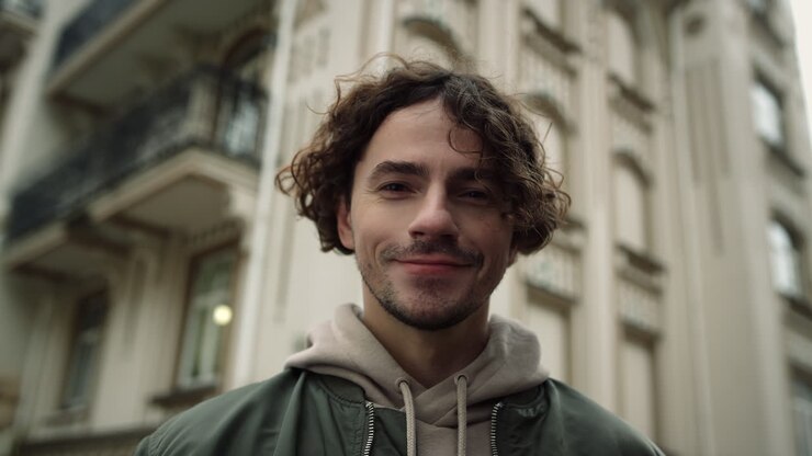 Bell'uomo in posa davanti alla fotocamera con lo sfondo della città. Ragazzo che sorride per strada in città.