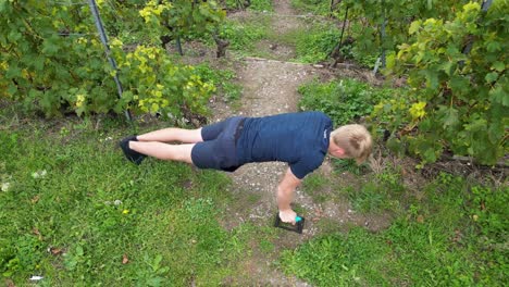 aerial, a young athlete does push-ups in a vineyard, lavaux, switzerland, exercising