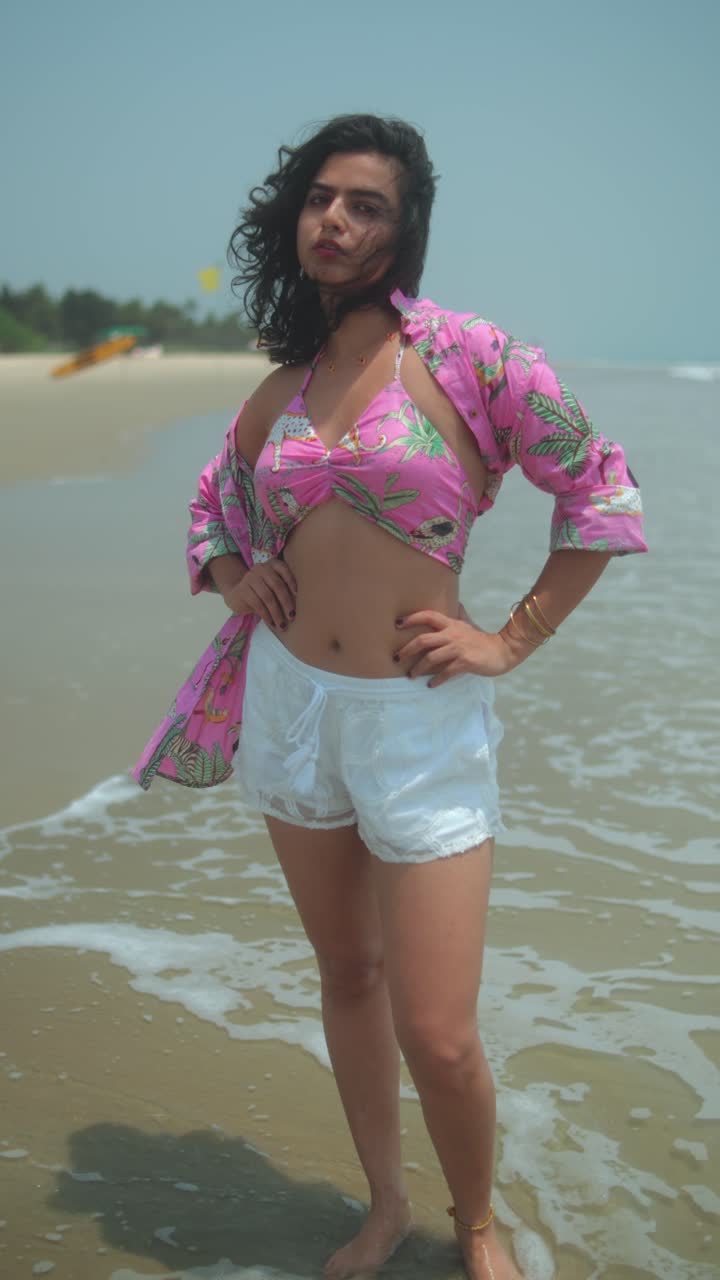 Confident woman posing on a tropical beach in summer outfit, hands on hips