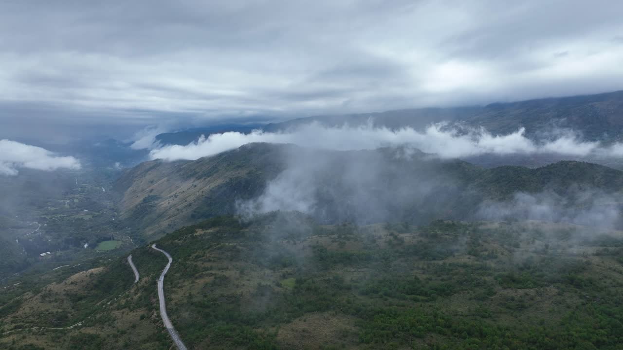 Drone view of foggy landcape of mountains with clouds on top during dawn in Cetinje, Montenegro.