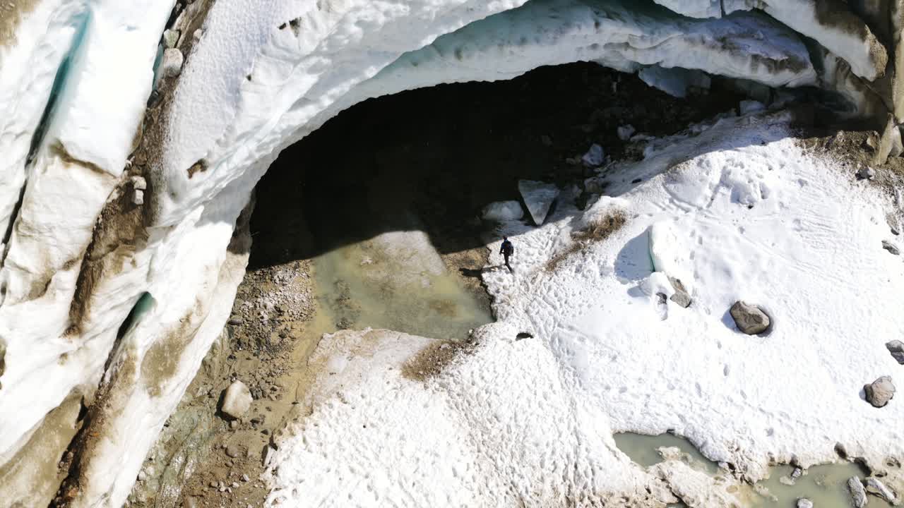 Aerial view of hiker entering massive ice cave at Morteratsch glacier, Switzerland