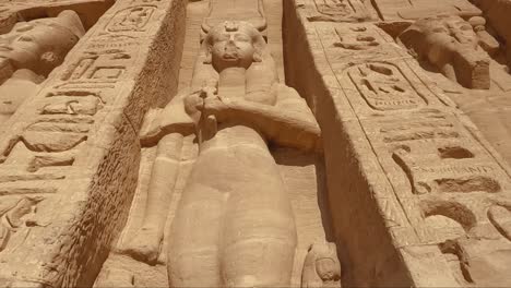 close-up of a central statue carved into the sandstone façade of the abu simbel temple in egypt. the sculpture, framed by intricate hieroglyphics and other pharaonic figures,.