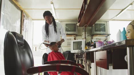 Fernsicht-Auf-Einen-Afrikanischen-Mann,-Der-Einem-Afrikanischen-Jungen-Die-Haare-Schneidet