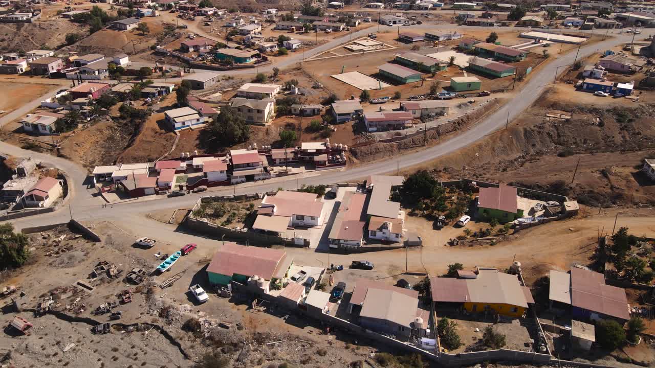 Aerial establishing orbit of Cedros Island’s fishing community in dry desert coastal terrain, cars hauling boats in trailers on dirt roads