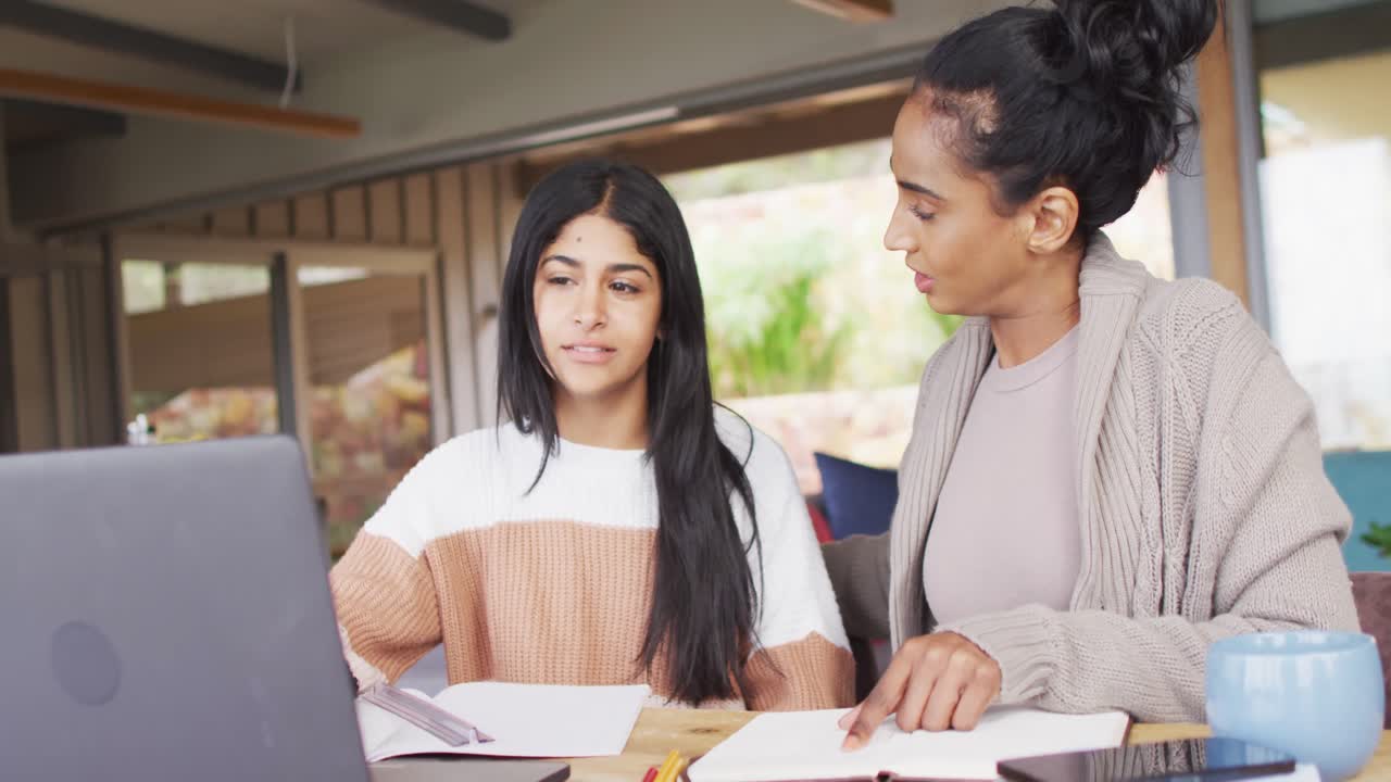 video de mujeres biraciales enfocadas trabajando desde casa con una computadora portátil