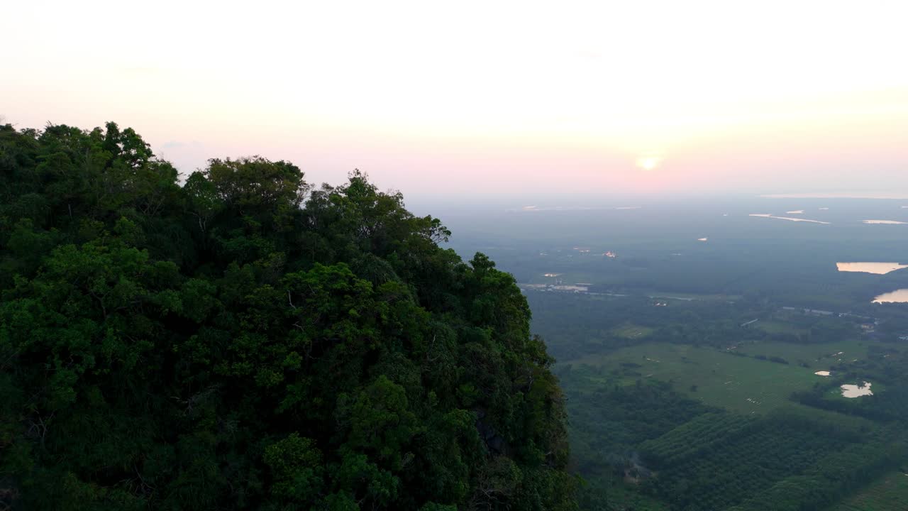 Aerial establishing shot of a dense jungle on the side of a cliff in Surat Thani