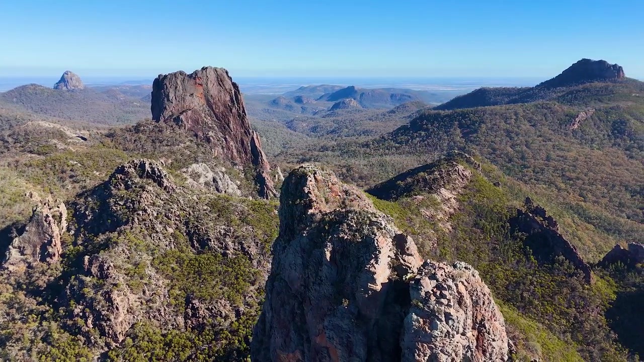 Voo de drone sobre pináculos de rocha vulcânica e mata nativa no Parque Nacional Warrumbungle, Austrália