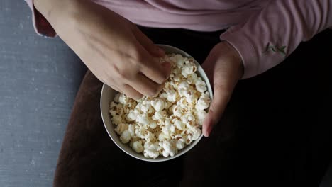 una mujer comiendo palomitas de maíz.