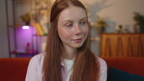 Close-up-of-happy-beautiful-young-redhead-child-girl-smiling-looking-at-camera-at-home-on-couch